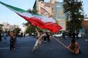 Demonstrators wave a huge Iranian flag in Tehran on April 15 (Vahid Salemi/AP)