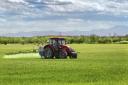 Farming tractor spraying on field