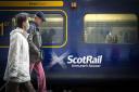 Two people walking in front of a Scotrail train. Credit: PA