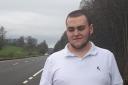 Councillor Conner Young at the side of the A985 road. He's backing a bus hub to improve transport links in West Fife.
