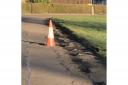The potholed road around the green, which the council have now agreed to repair. Image: Cllr Brian Goodall.